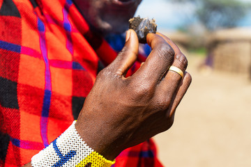 African man holding a smoldering cake in his hand with colorful bracelet.