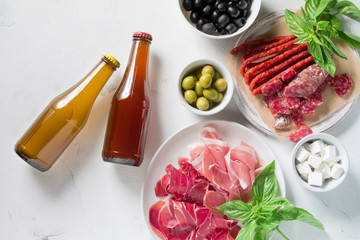 Set of jamon, chorizo sausages, olive, cheese and beer in bottles on a white background