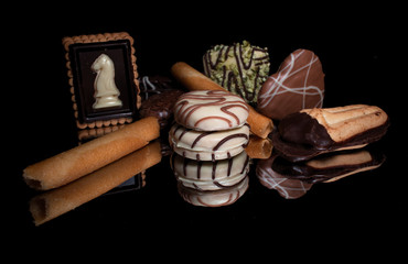 Sweet cookies and candies with reflection on shiny black background