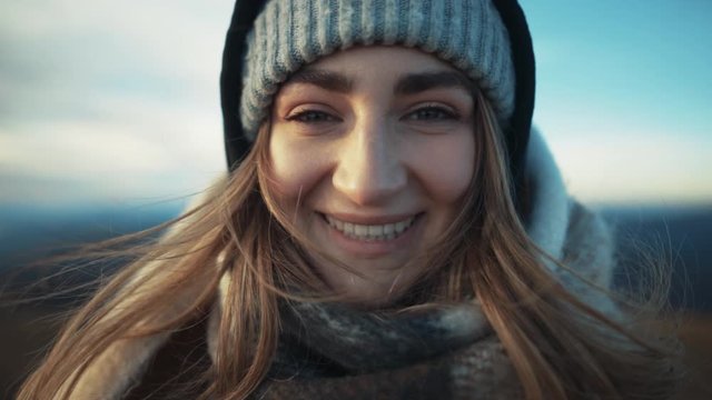Close up view of femail face. Charming young woman looks into the camera and smiles, the wind flutters hair trip adventure landscape outdoor pure nature slow motion portrait
