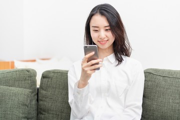 ソファに座って携帯電話を操作する女性
