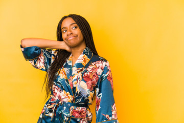 Young african american woman wearing an asiatic pijama isolated touching back of head, thinking and making a choice.