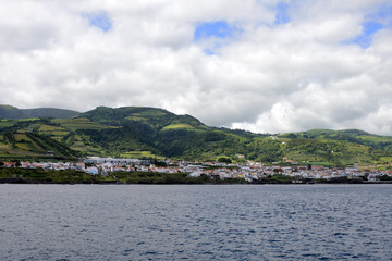 Fototapeta na wymiar Beautiful white clouds on the blue sky and coast of the city of Ponta Delgada, San Miguel Island, Portugal.