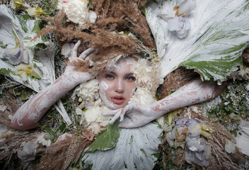 Female portrait in fairy tale stylisation surrounded with natural plants and flowers.