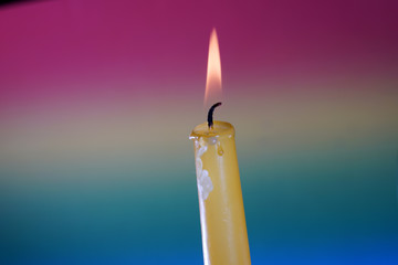 Yellow candle with smoke and flame photographed in the studio with color foils before the flashes