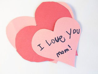 pink, red and white construction paper valentine craft hearts with "I love you" message written by a child