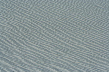 Background or Texture image with close-up of wave patterns on white gypsum dunes at White Sands National Park
