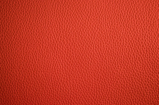 Leather texture close up. Orange fashionable background, top view. Stylish coral wallpaper with rough surface.