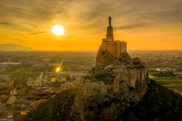 Aerial sunset view of Monteagudo castle built out of rammed earth with 2 enclosures following the...