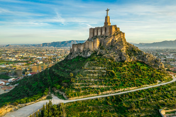 Aerial sunset view of Monteagudo castle built out of rammed earth with 2 enclosures following the...