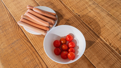 Wiener boiled sausages with cherry tomatoes on the wooden background.