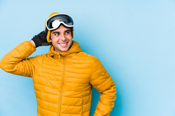 Fototapeta premium Young skier man wearing snowboard goggles isolated touching back of head, thinking and making a choice.