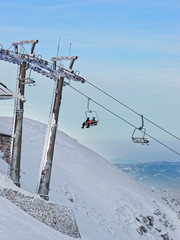 Fototapeta na wymiar Chair lifts with people in Kasprowy Wierch in Zakopane in winter. Zakopane is a town in Poland in Tatra Mountains. Kasprowy Wierch is a mountain in Zakopane and is the most popular ski area in Poland