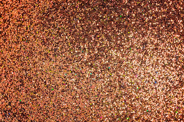 Bright shiny red-gold background for sites and layouts. The surface of many small sparkles, closeup. Selective focus.