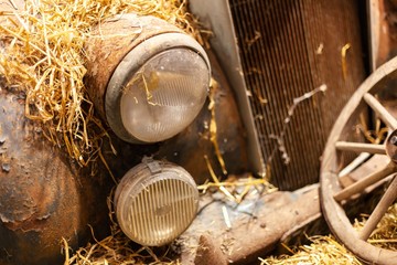 classic rusted car covered in hay in barn