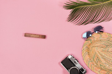 Travel vacation background concept. Sunglasses, hat, camera, palm leaves on pink background. Top view, copy space. Flat lay.