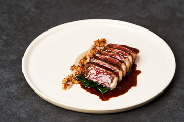 Sliced lamb meat and mashed potatoes on a white plate on gray table
