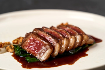 Sliced lamb meat and mashed potatoes on a white plate on gray table