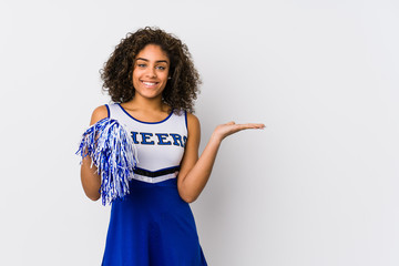 Young african american cheerleader woman isolated showing a copy space on a palm and holding...