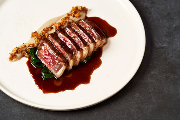 Sliced lamb meat and mashed potatoes on a white plate on gray table