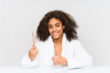 Young african american woman holding a toothbrush smiling and raising thumb up