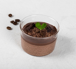 Italian dessert creamy chocolate and coffee jelly, Panna cotta with chocolate pieces in a glass Cup on a light background