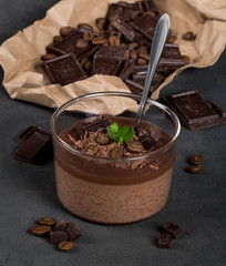 Italian dessert creamy chocolate and coffee jelly, Panna cotta with chocolate pieces in a glass Cup on a dark background