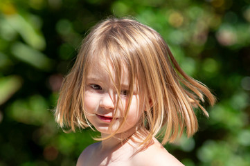 Smiling, excited little girl, about 4 years old, playing outside with her hair swinging out