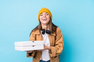 Young caucasian woman holding pizzas isolated laughing and having fun.