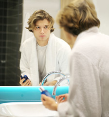 young man looking in the mirror,combing his hair,looking at problems on face