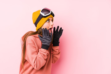 Young caucasian woman wearing a ski clothes isolated shouts loud, keeps eyes opened and hands tense.