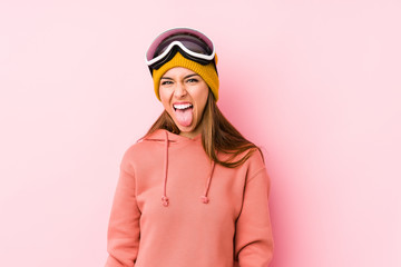 Young caucasian woman wearing a ski clothes isolated funny and friendly sticking out tongue.