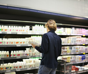 Teenager shopping in supermarket, reading product information	