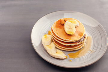Pancakes with banana nuts honey caramel syrup on a gray plate.  Breakfast