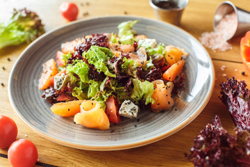 Lunch Time. Fresh salad with salmon and feta isolated on table surrounded by ingredients close-up