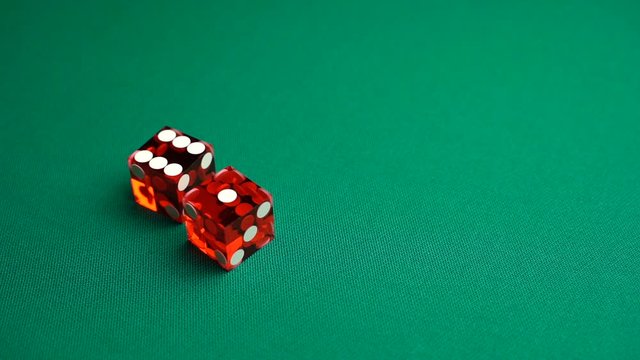 The shooter rolls seven in craps. Slow motion two red dice, craps, thrown on green tomentum background at casino, natural or seven out. Gambling game with random result for adults.