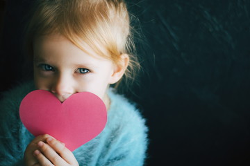 Portrait of a little girl holding big paper pink  handmade heart. Valentines concept. Child making valentine.