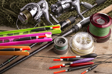 Fishing rods and spinnings in the composition with accessories for fishing on the old background on the table