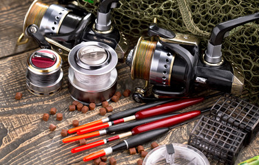 Fishing rods and spinnings in the composition with accessories for fishing on the old background on the table