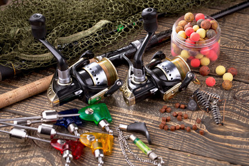 Fishing rods and spinnings in the composition with accessories for fishing on the old background on the table