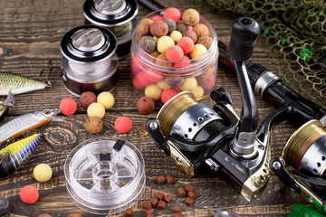 Fishing rods and spinnings in the composition with accessories for fishing on the old background on the table