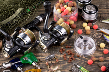 Fishing rods and spinnings in the composition with accessories for fishing on the old background on the table