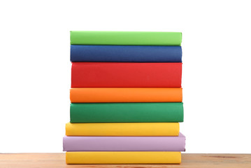 Stack of colorful books on wooden table against white background