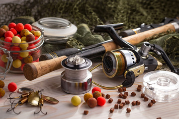Fototapeta na wymiar Fishing rods and spinnings in the composition with accessories for fishing on the old background on the table