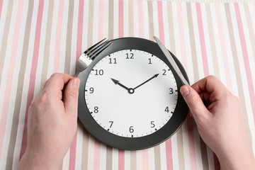 Men's hands hold power devices over a gray plate with a clock. Intermittent fasting concept, ketogenic diet. The current diet of the new 2020 to improve health.
