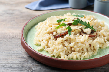 Delicious risotto with cheese and mushrooms on wooden table, closeup