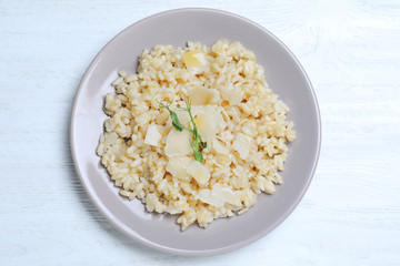 Delicious risotto with cheese on white wooden table, top view
