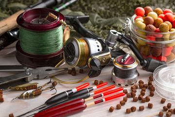 Fishing rods and spinnings in the composition with accessories for fishing on the old background on the table