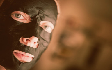 Close-up woman relaxing with a charcoal facial mask, concept health face