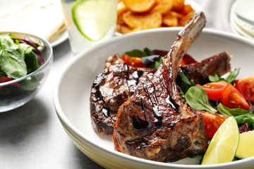 Delicious grilled ribs served on light grey table, closeup